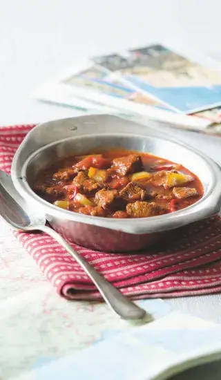 Maďarský vepřový perkelt s kořenovou zeleninou ve kovové misce.