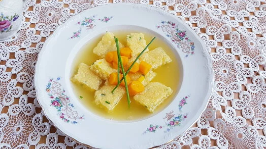 Mísa žluté polévky s knedlíčky a cibulkou.