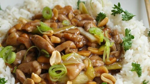 Hotovo kuřecí kung pao s rýží a opečenými arašidy.