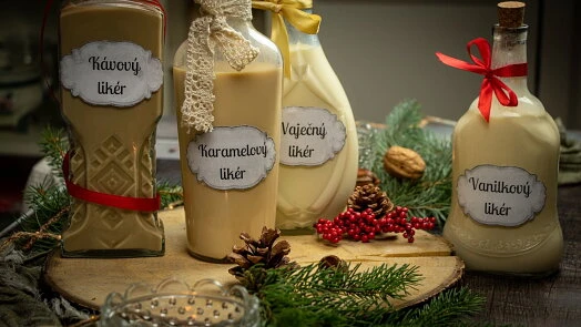 Čtyři lahve bezalkoholového likéru s vánoční výzdobou na dřevěném podstavci.