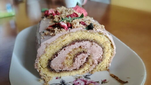 Kousek rolády s mascarpone a malinami na talíři.
