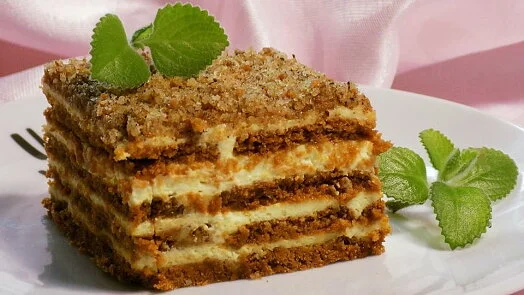 Kus dezertu s vrstvami tvarohové smetany a mramorovaného dortového těsta ozdobený mátou.