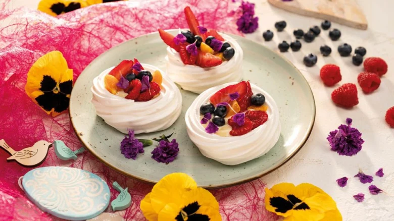 Tři dorty Pavlova s ovocem na talíři.