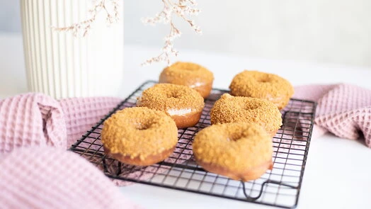 Zlatohnědé domácí pečené donuty s cukrem na mřížce.