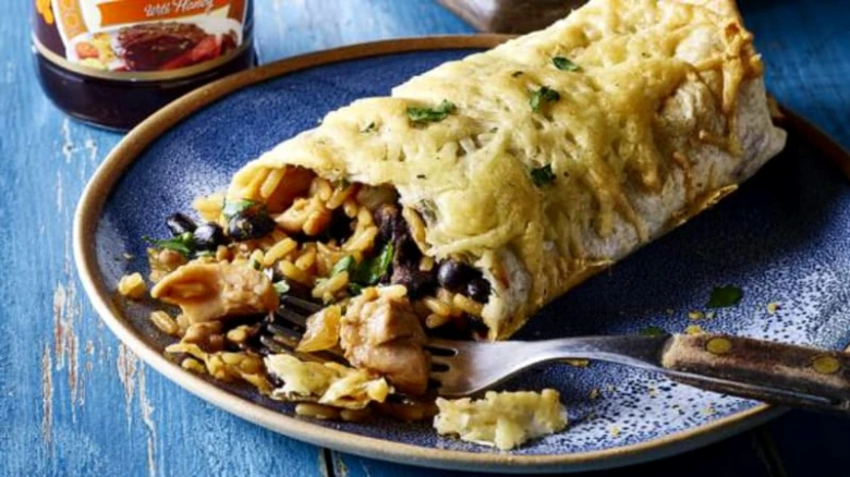 Zlatavý burrito s kuřetem, fazolí a rýží na modré talíři.
