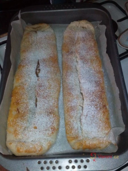 Dva pečené závině s jablky posypané moučkovým cukrem v plechu.