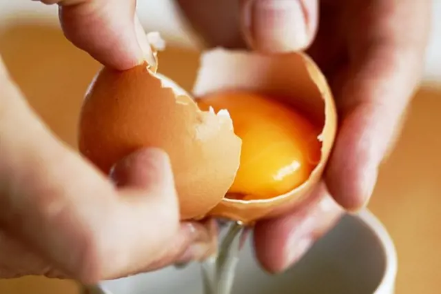 Ruční rozlupování vejce do misky pro recept volské oko.