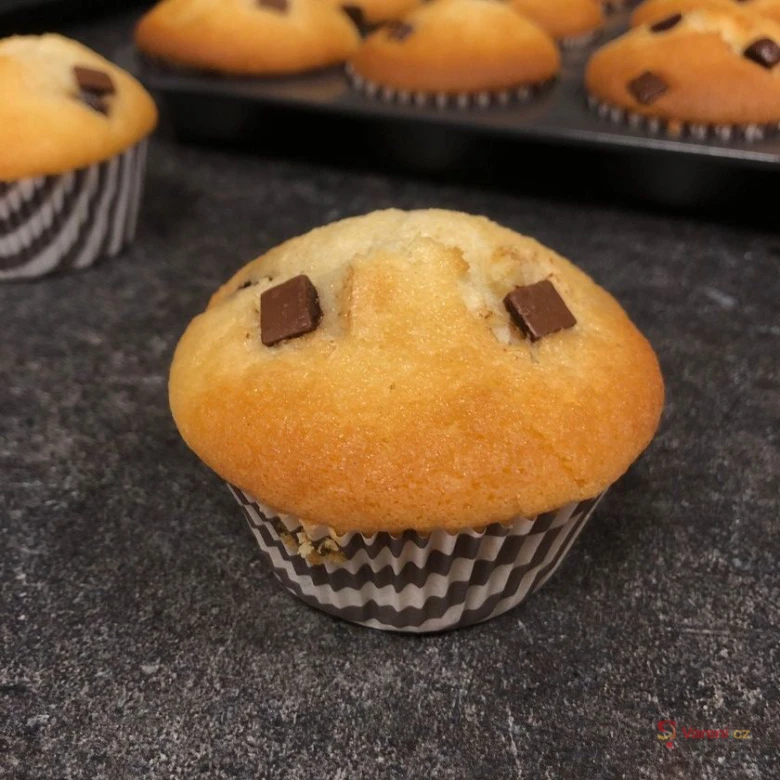 Domácí muffiny s čokoládovými kousky na tmavé desce.