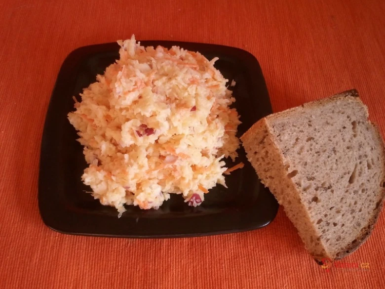 Čerstvý salát z křenu s mrkví podávaný vedle krajíce chleba.