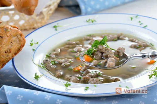 Hot bowl of Czech-style beef soup with tender meatballs in clear broth.