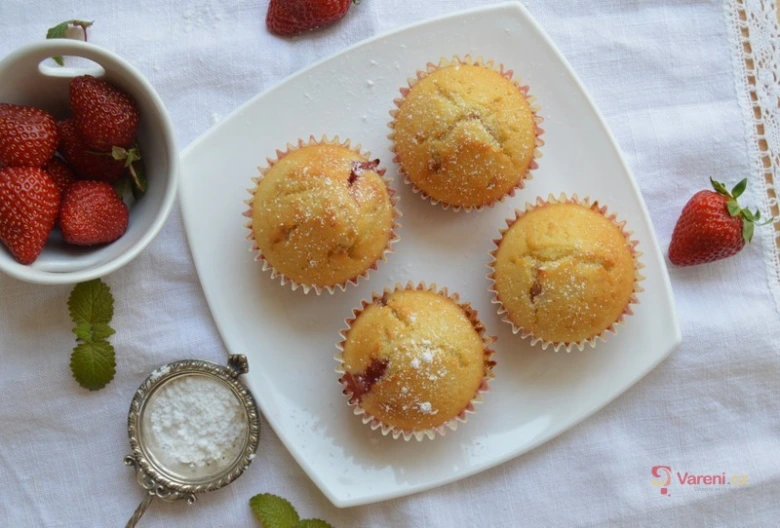 Čtyři muffiny s jahodami posypané cukrem na bílém talíři