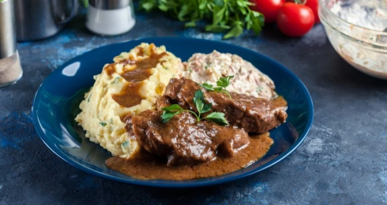 Maso v omáčce s bramborovou kaší na talíři.