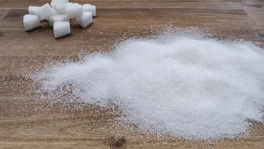 Bílý cukr v kostkách i granulované na dřevěném povrchu.