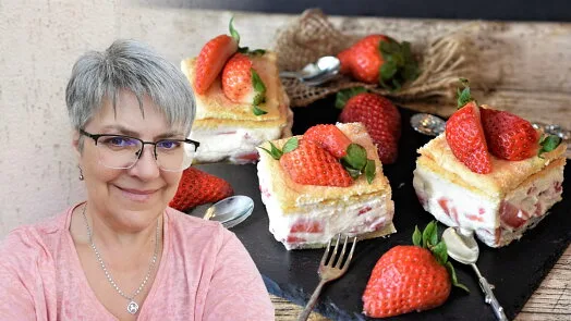 Kusy dortu s jahodami a krémem na černém podnose.