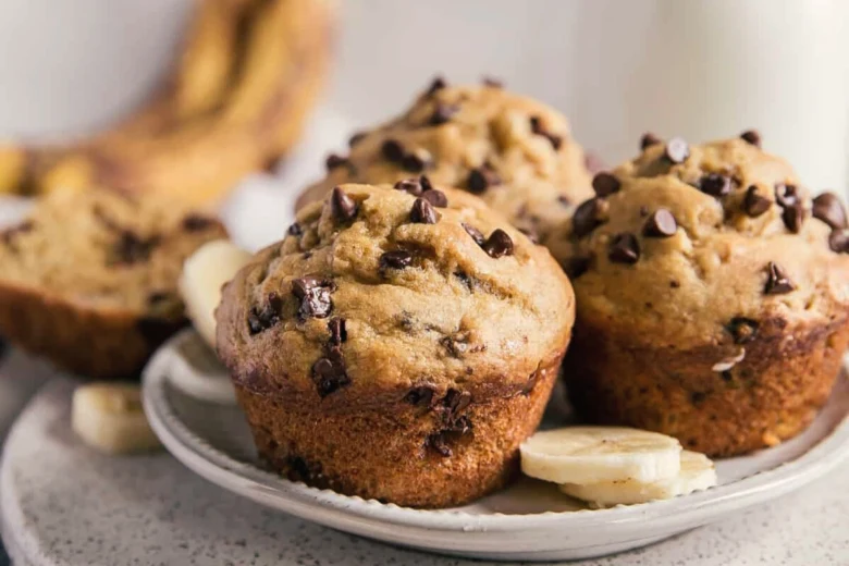 Tři banánové muffiny s čokoládovými kousky na talíři.