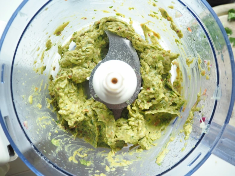 Guacamole v mixéru po zpracování s viditelnou texturou avokáda.
