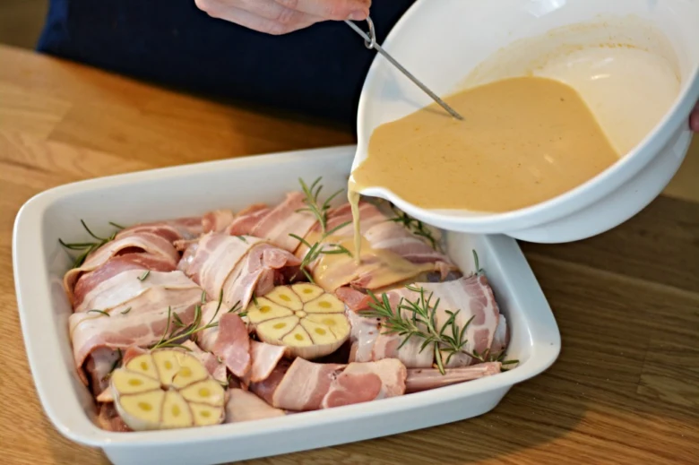 Příprava pečeného králíka s vepřovým balem, česnekem a rozmarýnem.