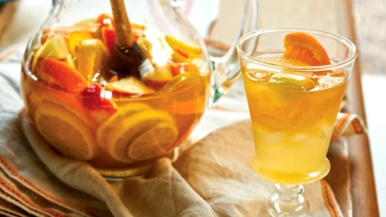 Sklenice s sangrií plná ovocných kousků vedle džbánu.