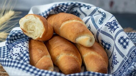 Zlatohnědé domácí rohlíky v košíku s modrobílým ubrouskem.