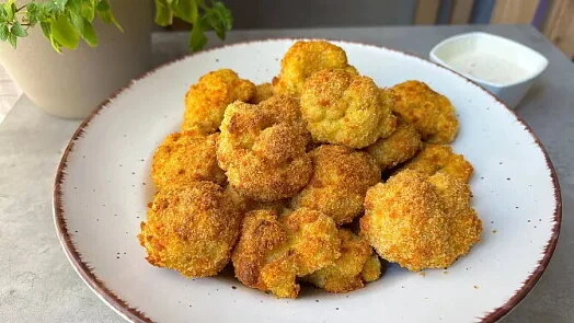 Zlatohnědé obalené smažené květákové růžičky na talíři.