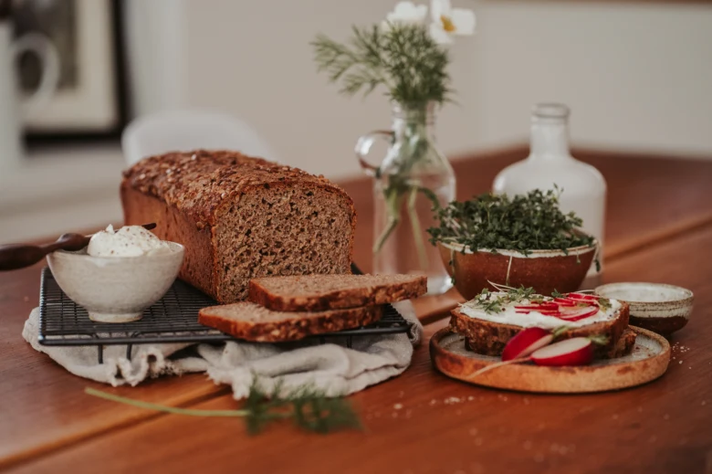 Domácí žitný chléb s krémem a ředkvičkami na stolu.