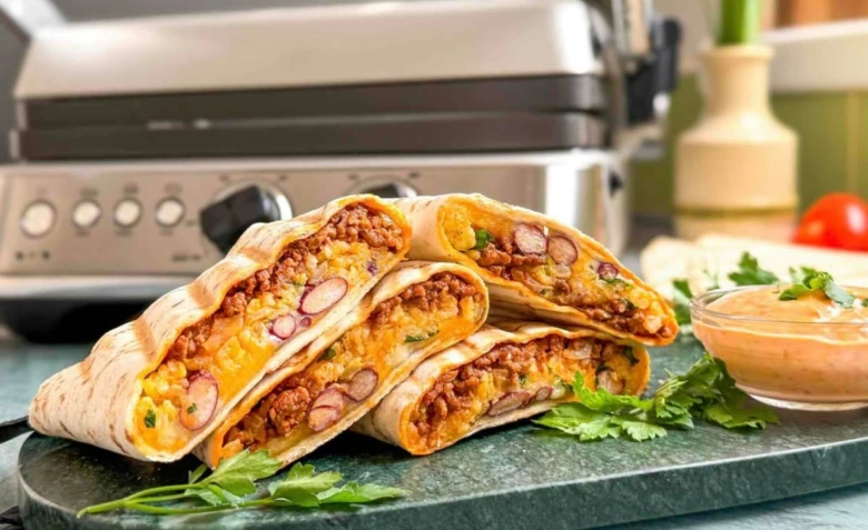 Nakrájené domácí burrito s masem a fazolemi na talíři.