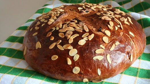 Zlatohnutý mazanec s mandlovými plátky na zeleno-bílé ubrus.