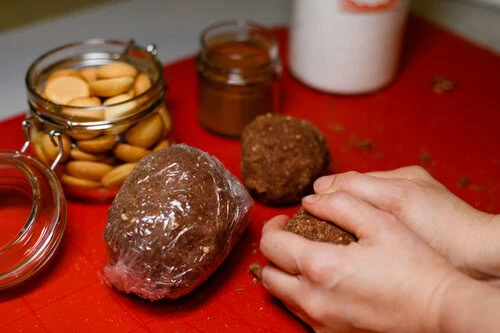 Ruce tvarují koule z těsta na cukroví s surovinami v okolí.