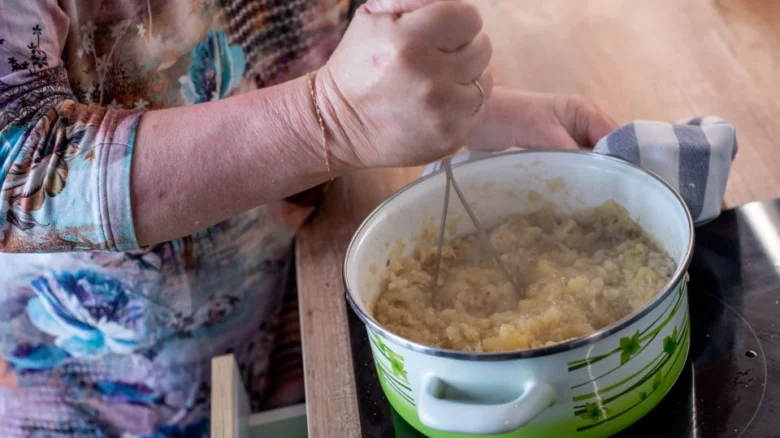 Člověk míchá dušenou kapustu v hrnci na indukční varné desce.
