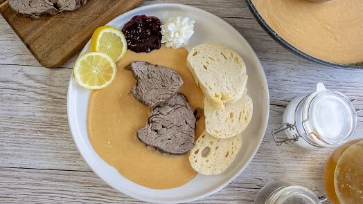 Položka svíčková s omáčkou na talíři se žitným chlebem.