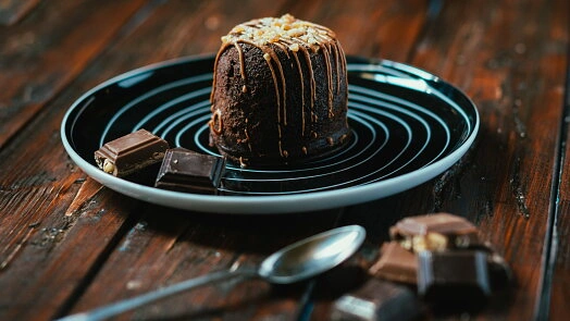 Čokoládový fondant s ořechy, čokoláda lomena na dřevěném stole.