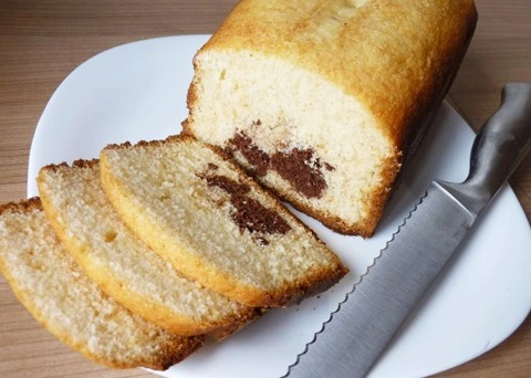 Nakrájená hrnková bábovka s čokoládovou náplní na bílém talíři.