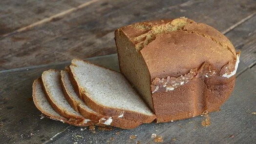 Kousek domácího podmáslového chleba s viditelnou kůrou.