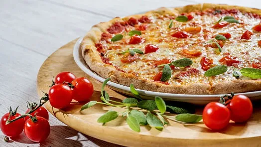 Připravená italská pizza s rajčaty a bazalkou na dřevěném podnosu