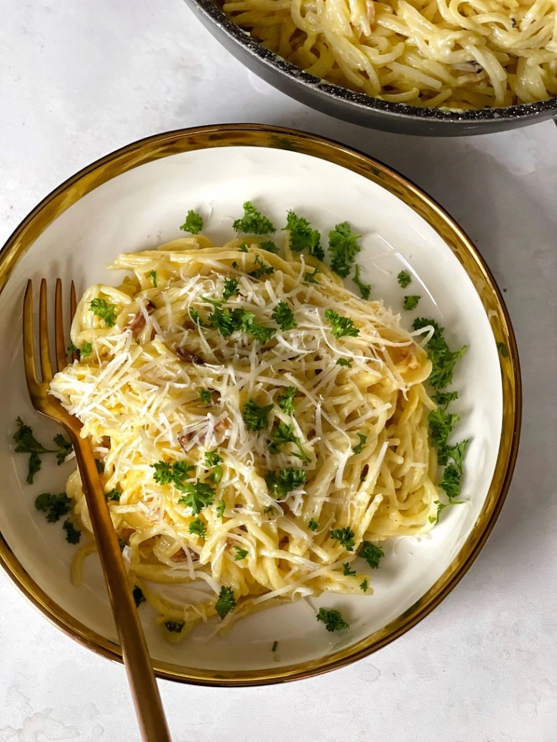 Miska s špagetami na omáčce carbonara posypaná syrem.