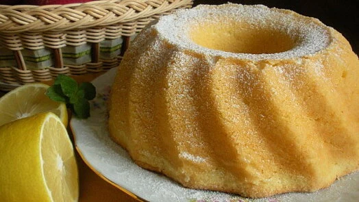 Citronová bábovka s jogurtem posypaná cukrem na talíři.