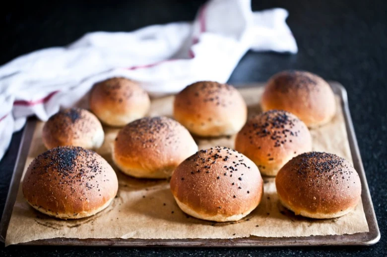 Zlaté domácí hamburgerové housky s hroznovým semínkem na plechu.