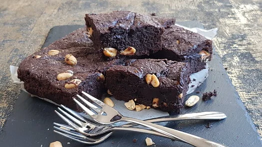 Čokoládové brownies s ořechy na šedém podnosu.