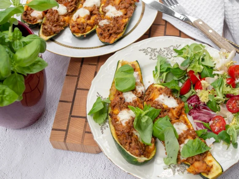 Stuffed baked zucchini boats with meat sauce and salad