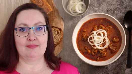 Žena s hovězím gulášem, chlebem a cibulí na talíři.