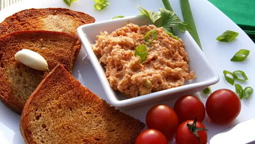 Tvarůžkový tatarák v bílé misce s toastem a rajčaty.