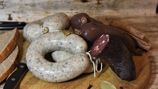 Surové vepřová srdce s klobásami na dřevěném prknu.