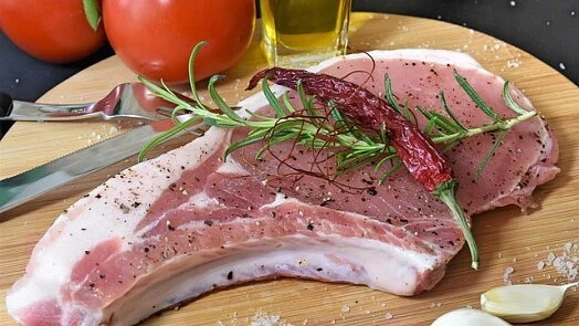 Surové vepřové plátky s bylinkami, česnekem a kořením na dřevěném prknu