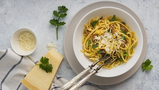 Mísa se špagetami, česnekem, olivovým olejem, parmezánem a petrželkou.
