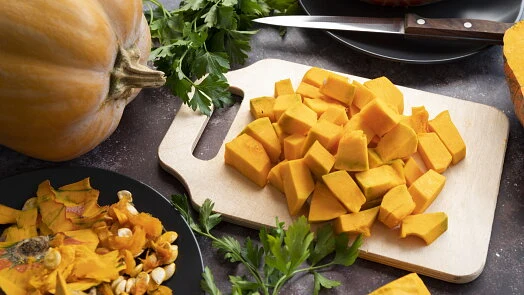 Nařezaný dýňový recept s čerstvou petrželkou na dřevěném prkénku.