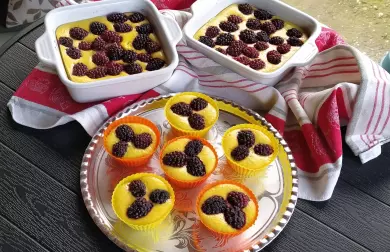 Borůvkové dezerty v keramických misích i jako muffiny na tmavém dřevěném povrchu.