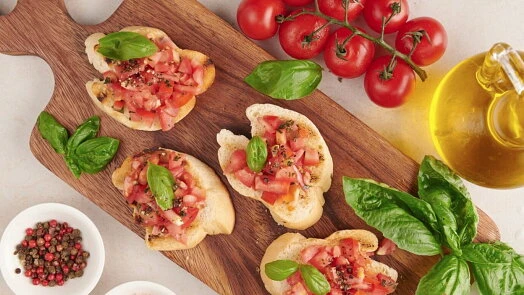 Italská bruschetka s rajčaty, bazalkou na dřevěném podnose.