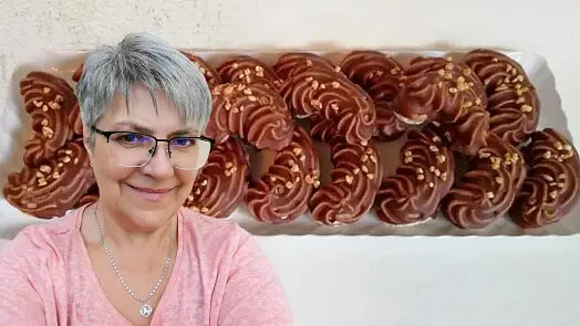 Žena stojí před táckem s čokoládovými sušenkami.