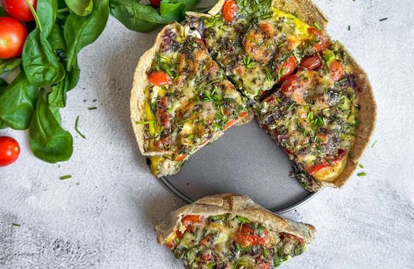 Připravená pizzy z tortilly s zeleninou a bylinkami.